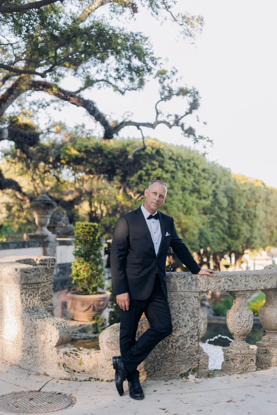 Groom portrait beside a stone garden balustrade