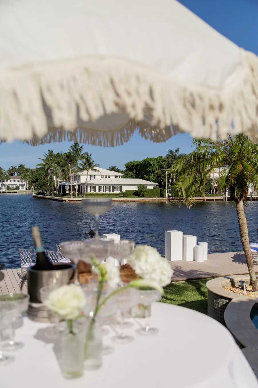 Waterfront wedding reception table with white floral arrangements